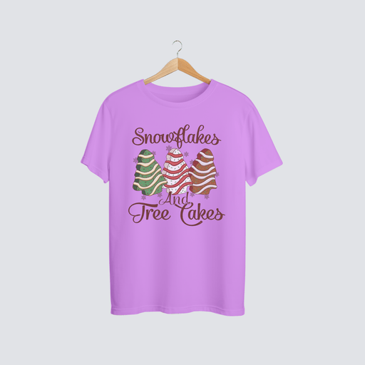 Snowflakes & Tree Cakes Christmas Tee displayed on a pink shirt, featuring colorful tree cake designs.